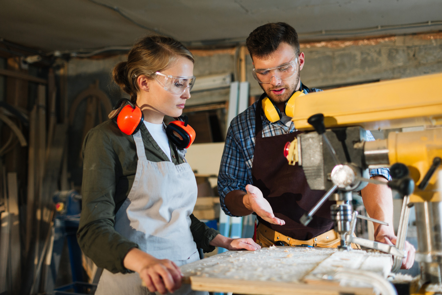 A young female in front of a machine listening to a mentor.