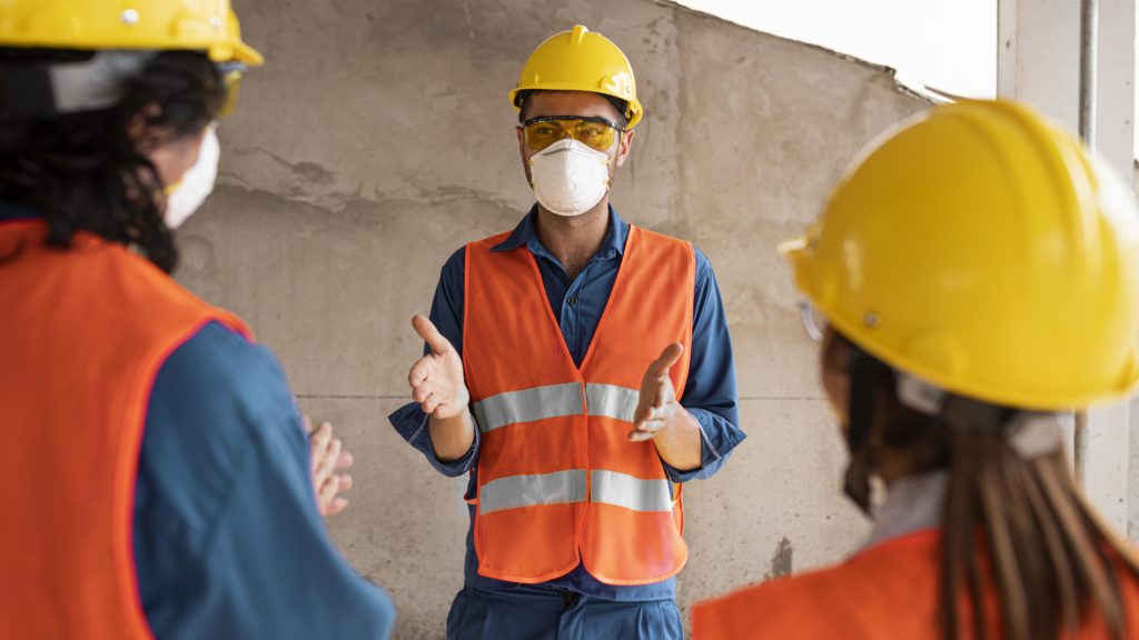 Employees discussing health and safety wearing safety equipment